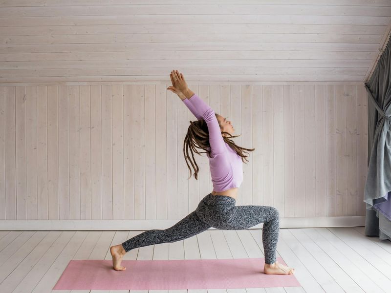 A person moving through a sequence of yoga poses in a bright room.